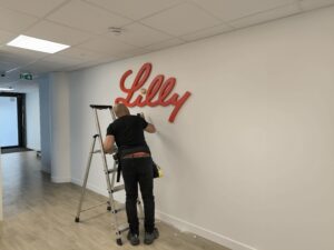 Pose d'un logo mural en lettres relief rouge dans des bureaux professionnels à Lyon, réalisée par Signarama Dardilly, spécialiste signalétique ouest Lyon